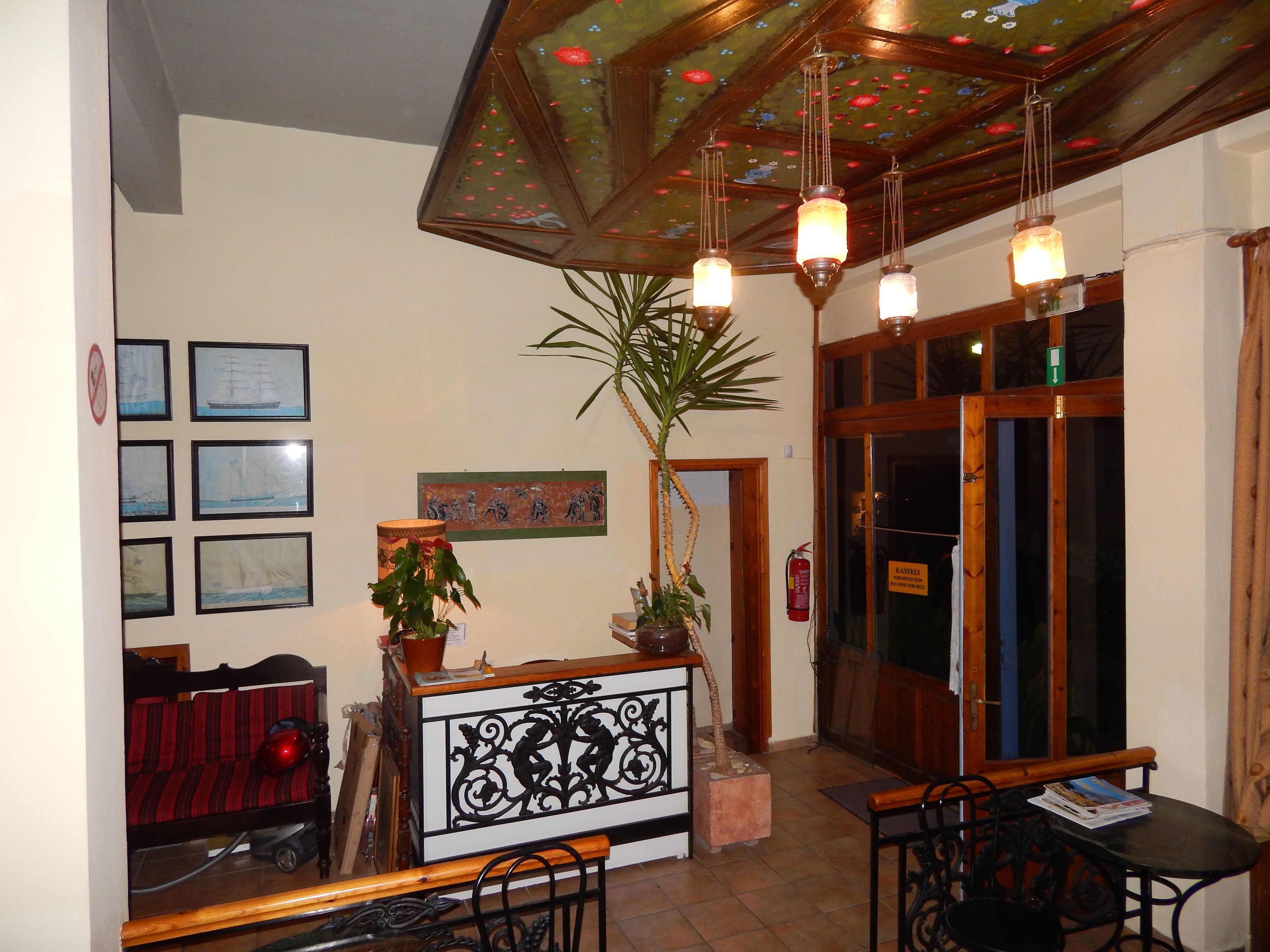 A reception area with a wooden reception desk, framed artwork on the wall, a potted plant, and a fire extinguisher.