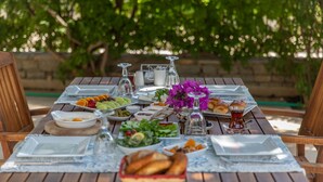 A wooden dining table set with various dishes, glasses, and a vase of flowers. - Ipek Garden Palace Residence - Boutique Class (Bodrum)