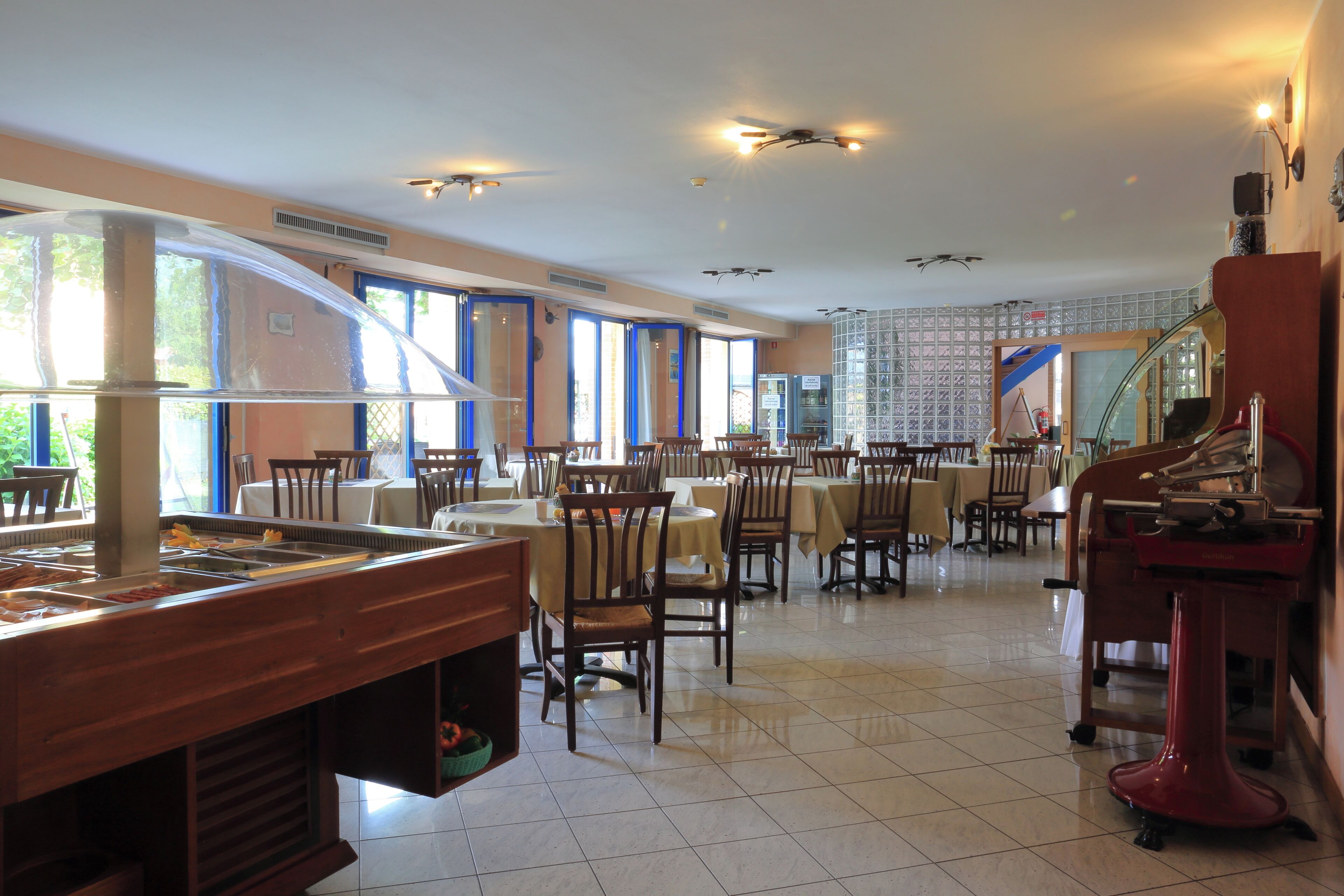 A restaurant with multiple tables and chairs, a buffet area, and a staircase leading to an upper level.