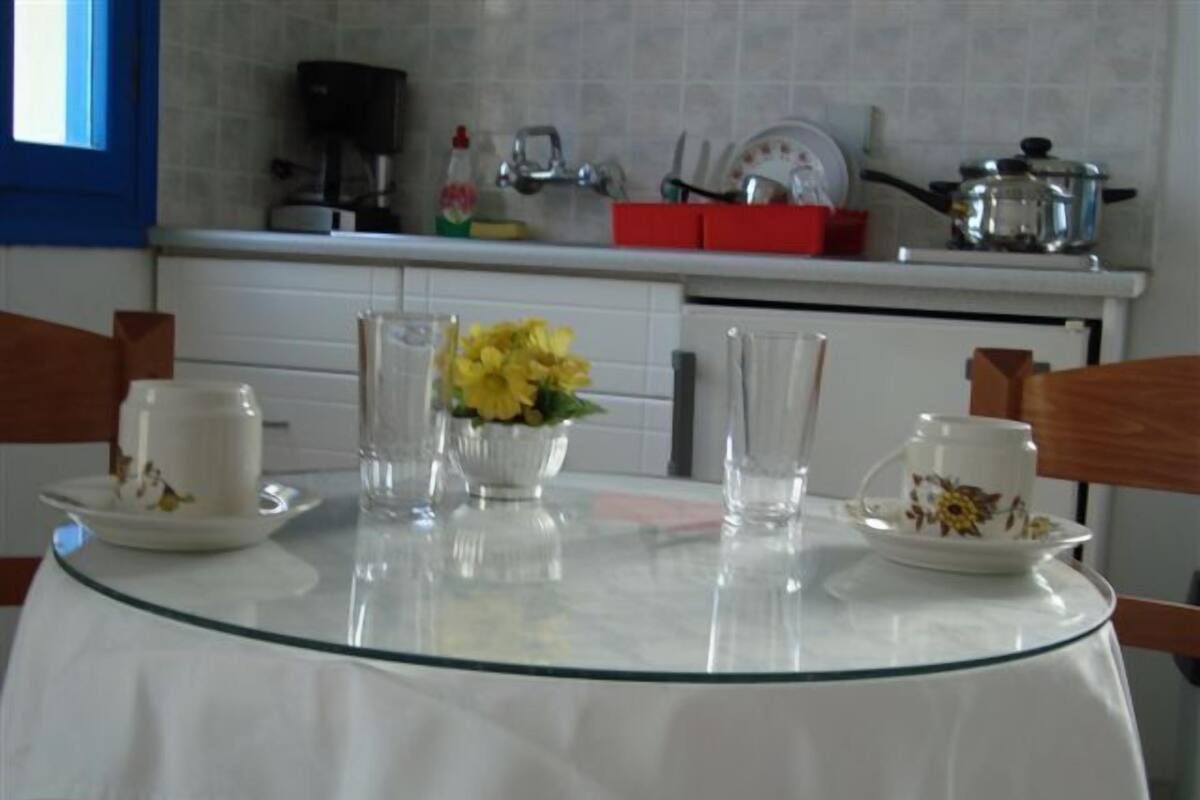 A kitchen with a glass table, white cabinets, and a red dish rack.