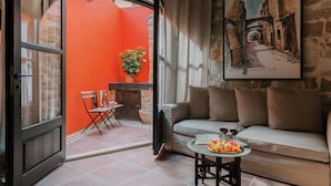 A cozy room with a wooden ceiling, a sofa, a small table with a plate of food and wine glasses, and a painting on the wall. - Zacosta Villa - a Heritage Hotel (Rhodes)