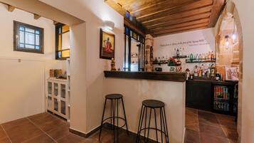 Un espace bar avec des tabourets, un comptoir et des étagères remplies de bouteilles.