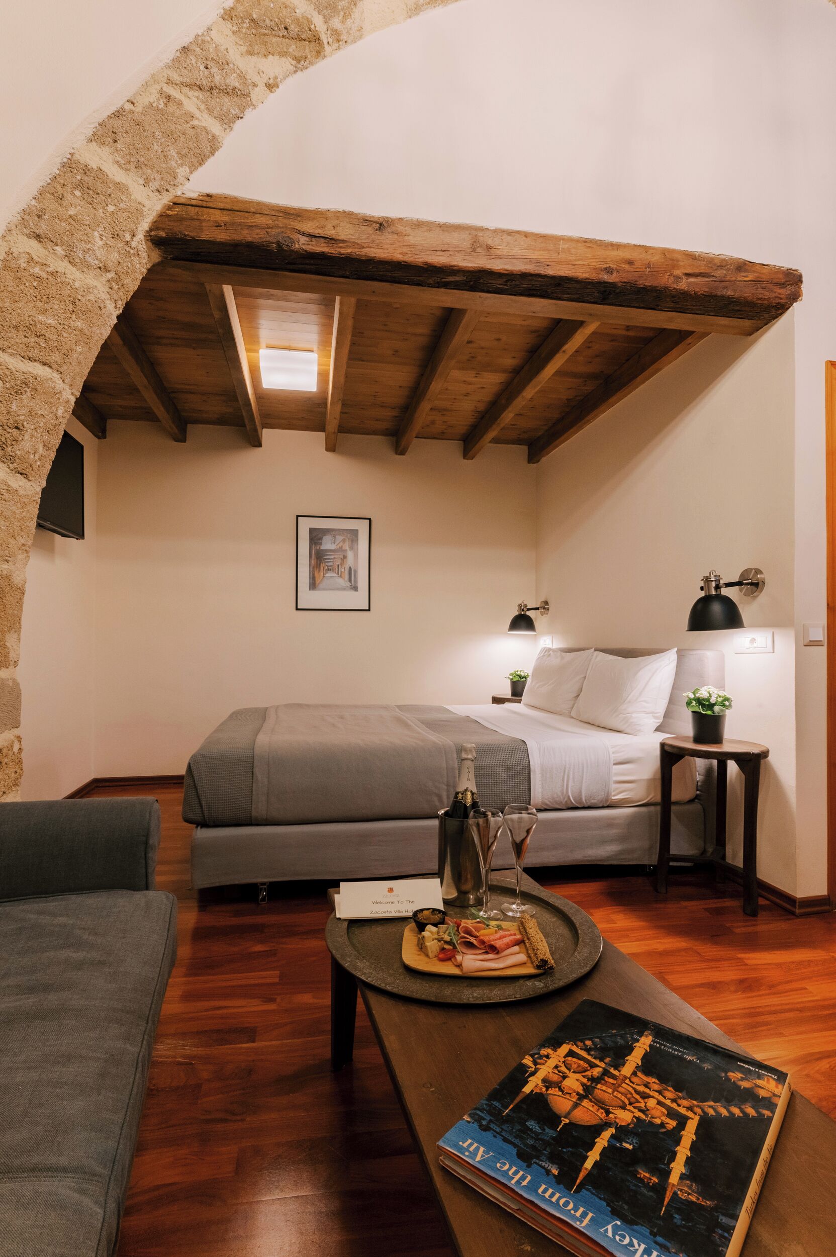 Une pièce confortable avec un lit, une petite table sur laquelle se trouve un plateau de nourriture, un livre et une lampe.