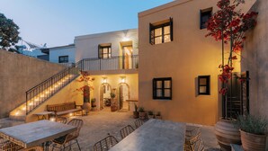 A courtyard with outdoor seating, a staircase, and a building with multiple windows and doors. - Zacosta Villa - a Heritage Hotel (Rhodes)