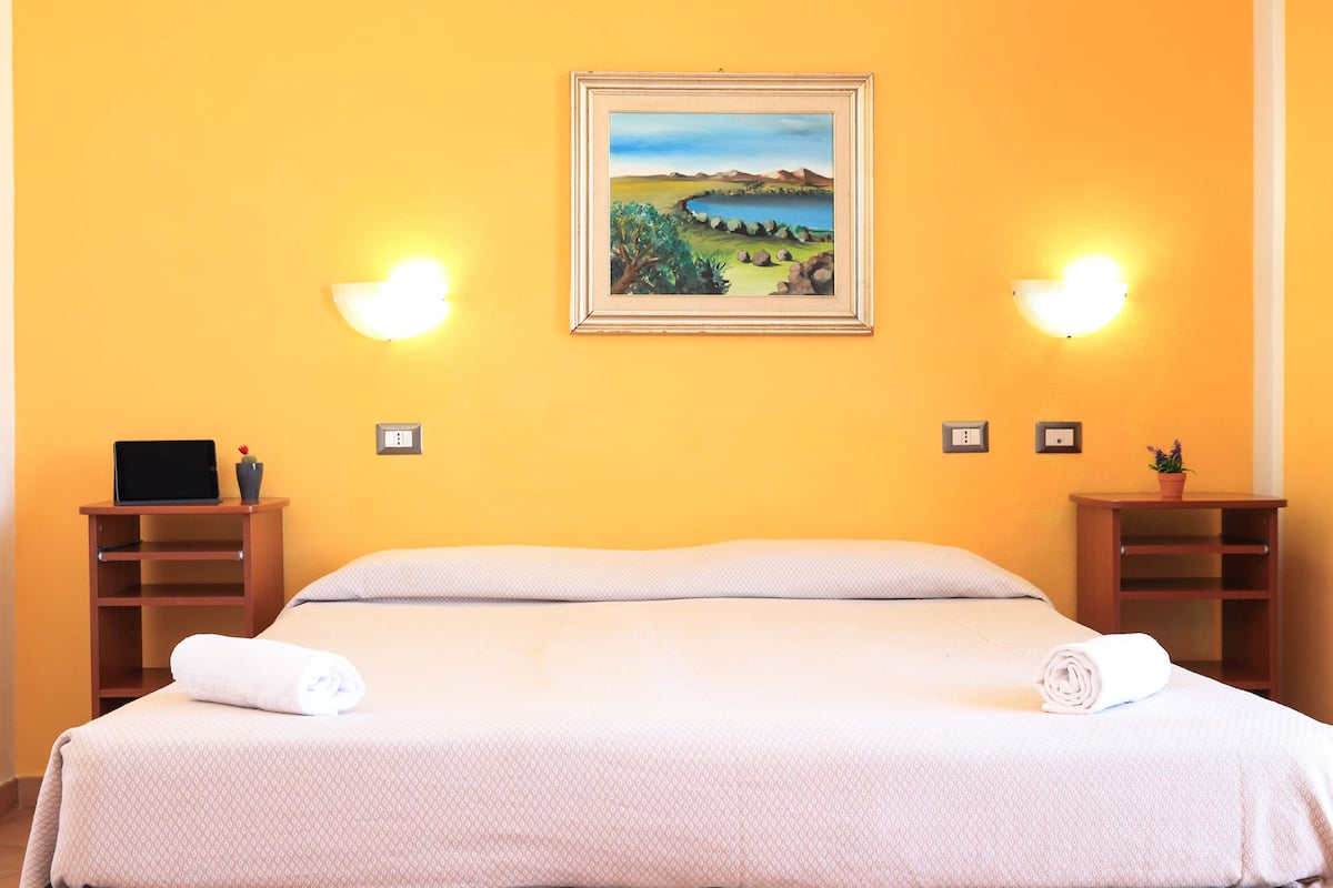 Ein Hotelzimmer mit einem Bett, zwei Nachttischen, einem Gemälde und Wandleuchten.