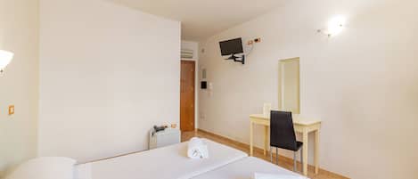 A hotel room with two beds, a desk, a chair, a TV, and a mirror.