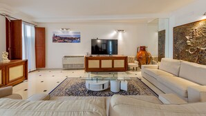 A modern living room with a sofa, a TV, a coffee table, and a decorative vase. - Hotel Villa Piras (Alghero)