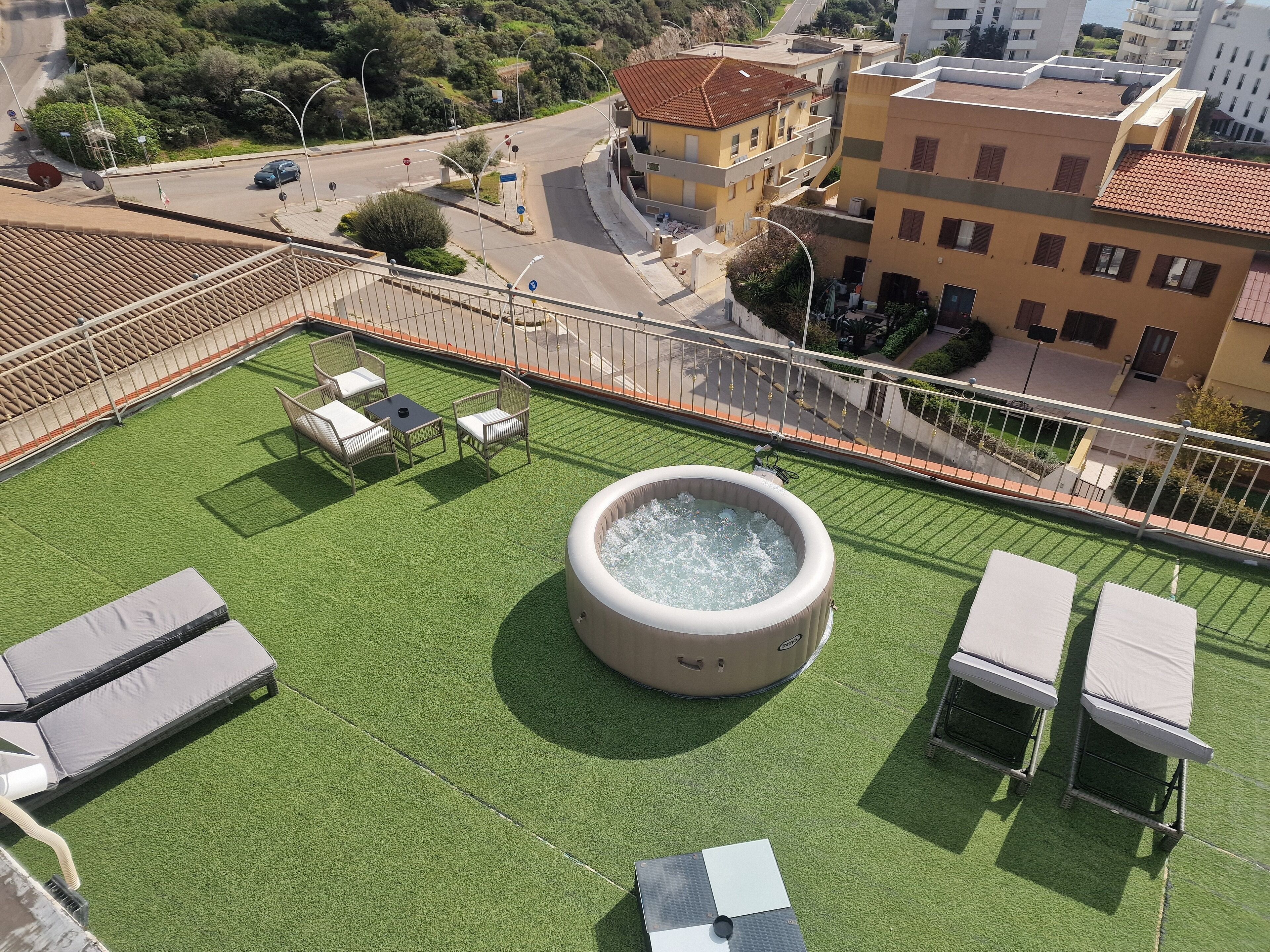 A rooftop terrace with artificial grass, a hot tub, and outdoor seating.