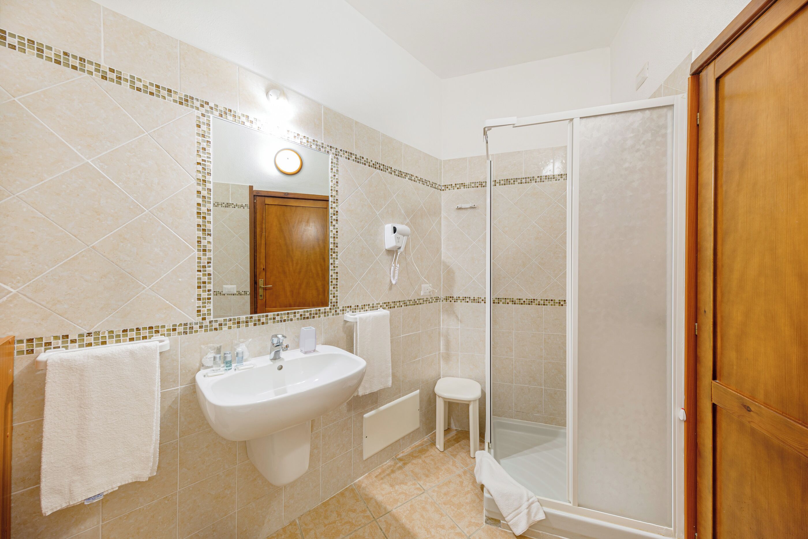 Une salle de bain équipée d’un lavabo, d’un miroir, d’un porte-serviettes et d’une douche.