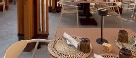 Een buiten eethoek met tafels en stoelen, beschaduwd door grote parasols, omgeven door verticale houten panelen.