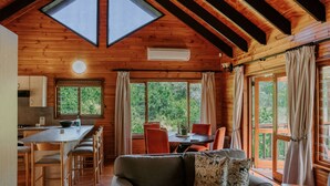 A cozy cabin with a wooden interior, a dining area, and large windows offering a view of the outdoors. - Thunzi Bush Lodge (Gqeberha (Port Elizabeth))