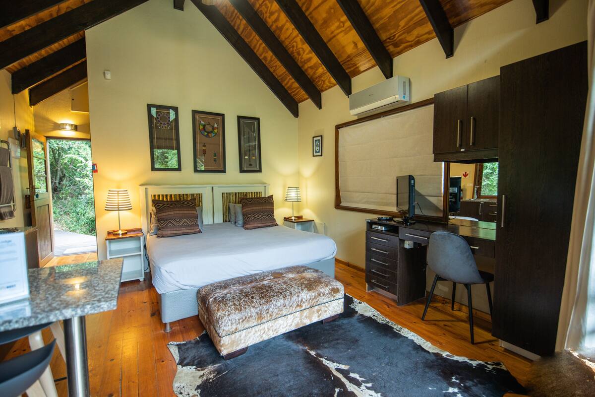 A bedroom with a bed, bedside tables, a desk, and a chair.
