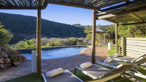 A poolside area with lounge chairs, a pergola, and a view of a mountainous landscape. - Thunzi Bush Lodge (Gqeberha (Port Elizabeth))