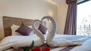 A hotel room with a neatly made bed, a headboard, a window with curtains, and a view of the outdoors. - Edom Hotel (Wadi Musa)