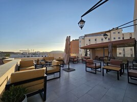 Una terraza en la azotea con mobiliario exterior, una farola y vistas de la ciudad.