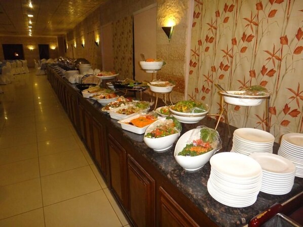 Una barra de buffet con diversos platos y una pila de platos blancos.