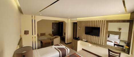 A hotel room with two beds, a desk, a TV, and a mirror.