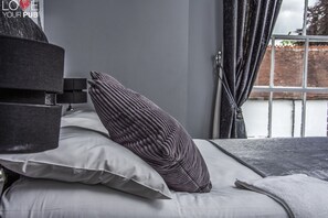A bed with a grey headboard, a striped pillow, and a white pillow. - Robin Hood Inn (Rowlands Castle)