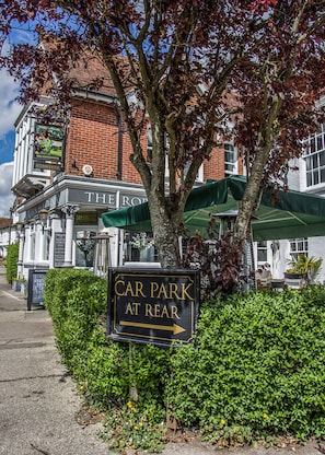 A sign for a car park at the rear of a building with a brick facade and a green awning. - Robin Hood Inn (Rowlands Castle)