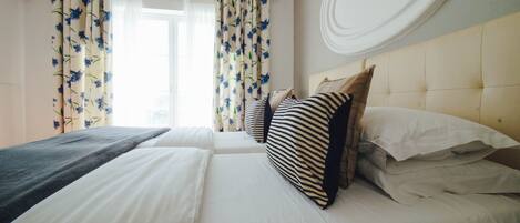 A hotel room with a bed, pillows, a headboard, and curtains.