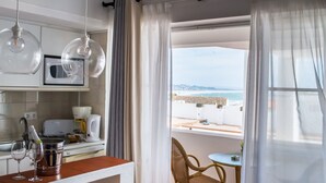 Eine Küche mit Meerblick, ein Essbereich mit Tisch und Stühlen sowie ein Fenster mit transparenten Vorhängen.