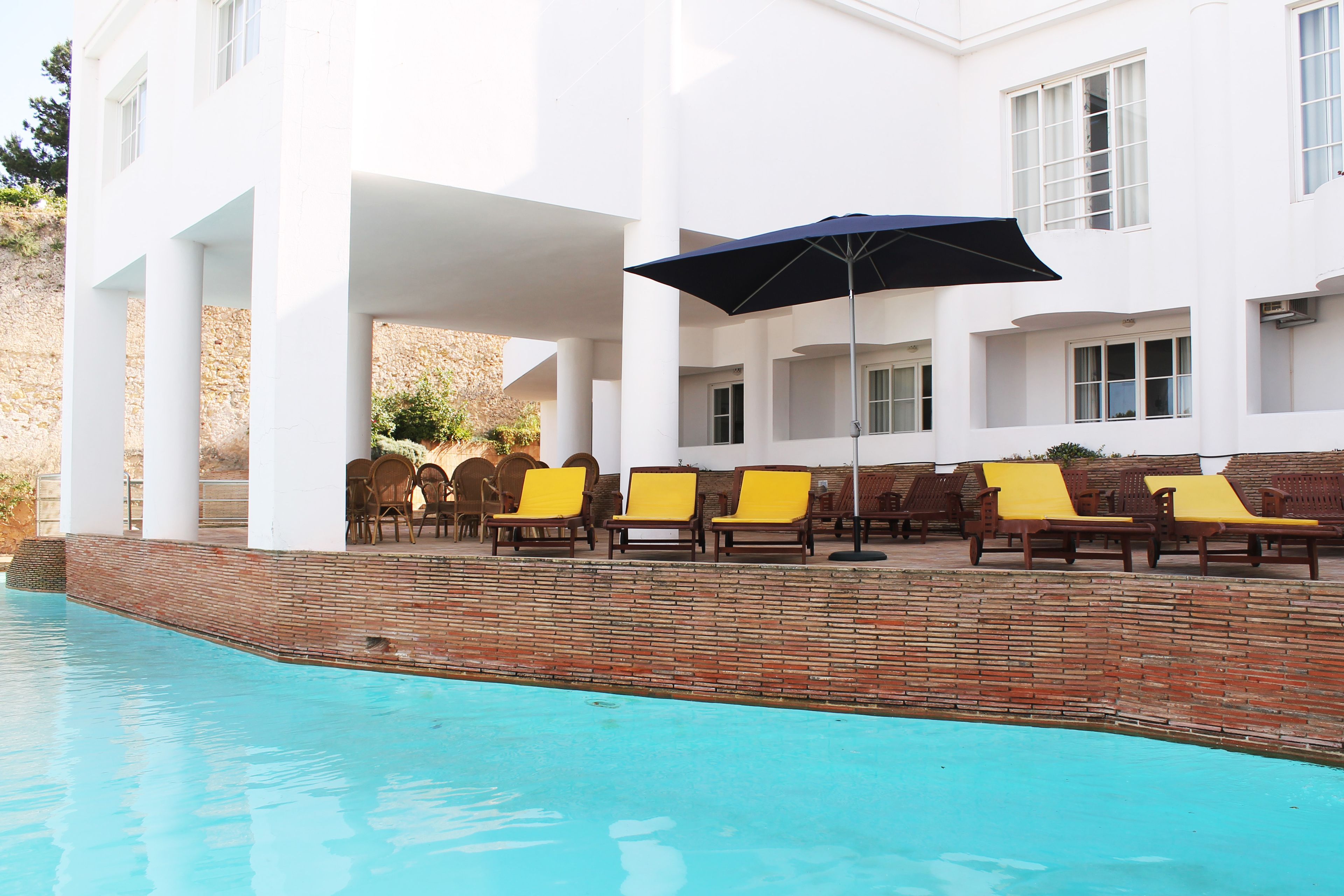 A pool area with lounge chairs and an umbrella.