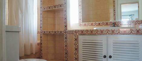 A bathroom with a toilet, shower, and sink.