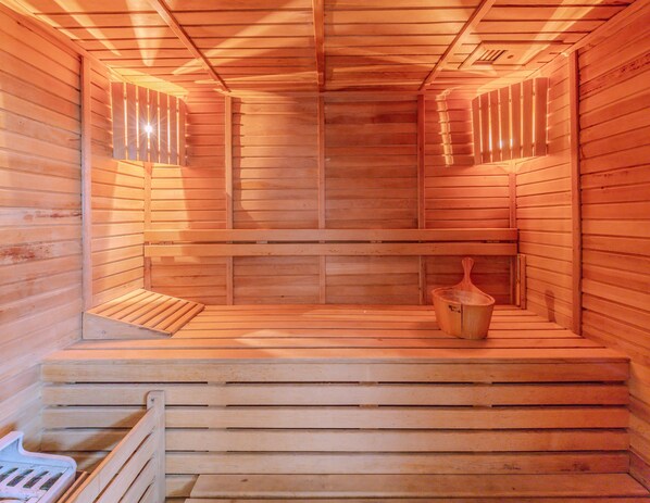 A wooden sauna with benches and a wooden bucket.