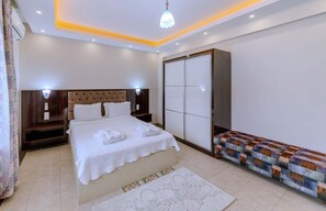 A bedroom with a bed, bedside tables, a bench, a wardrobe, and a ceiling light fixture. - Dundar Thermal Villa Otel (Afyonkarahisar)