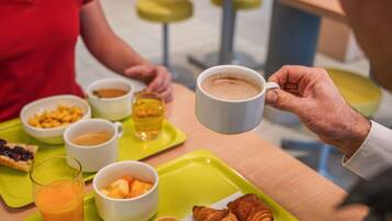 A breakfast setting with a tray containing croissants, fruit, and a glass of orange juice.