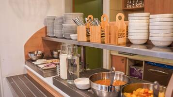 Disposição de buffet com diversos alimentos, utensílios e recipientes.