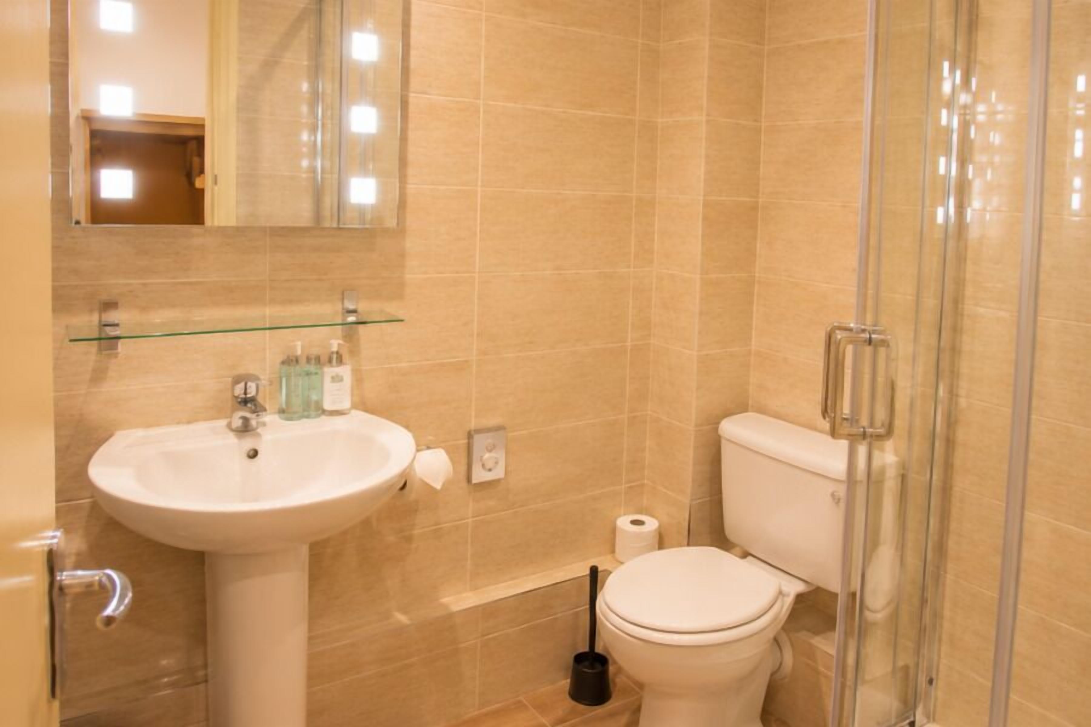 Un baño con lavabo, inodoro y cabina de ducha de cristal.