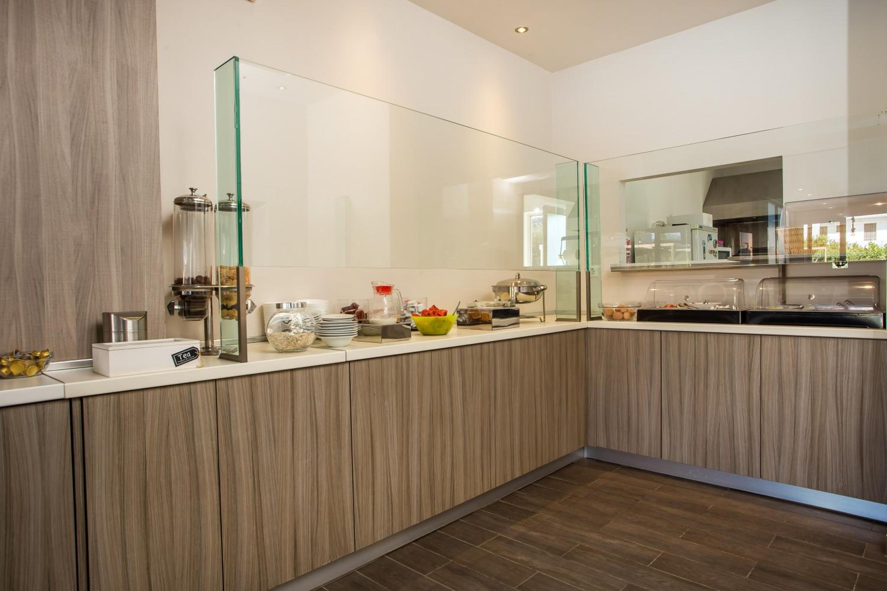 Una cocina moderna con un armario de madera, un especiero con puertas de vidrio y un lavamanos de acero inoxidable.