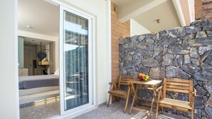 A balcony with a stone wall, a wooden table, and two wooden chairs. - Dias Studios (Rhodes)