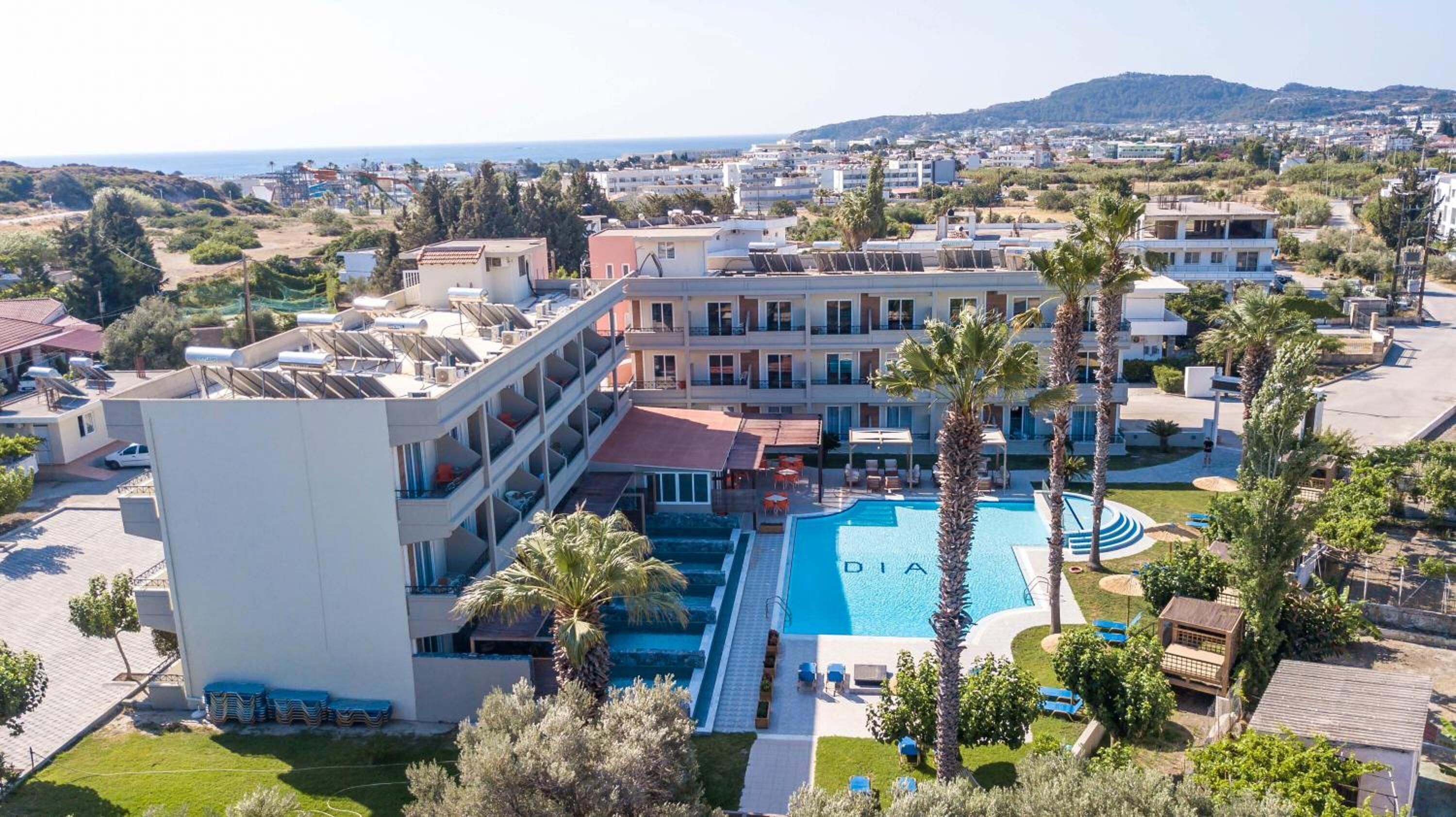A hotel with a swimming pool, multiple floors, and a view of the surrounding area.