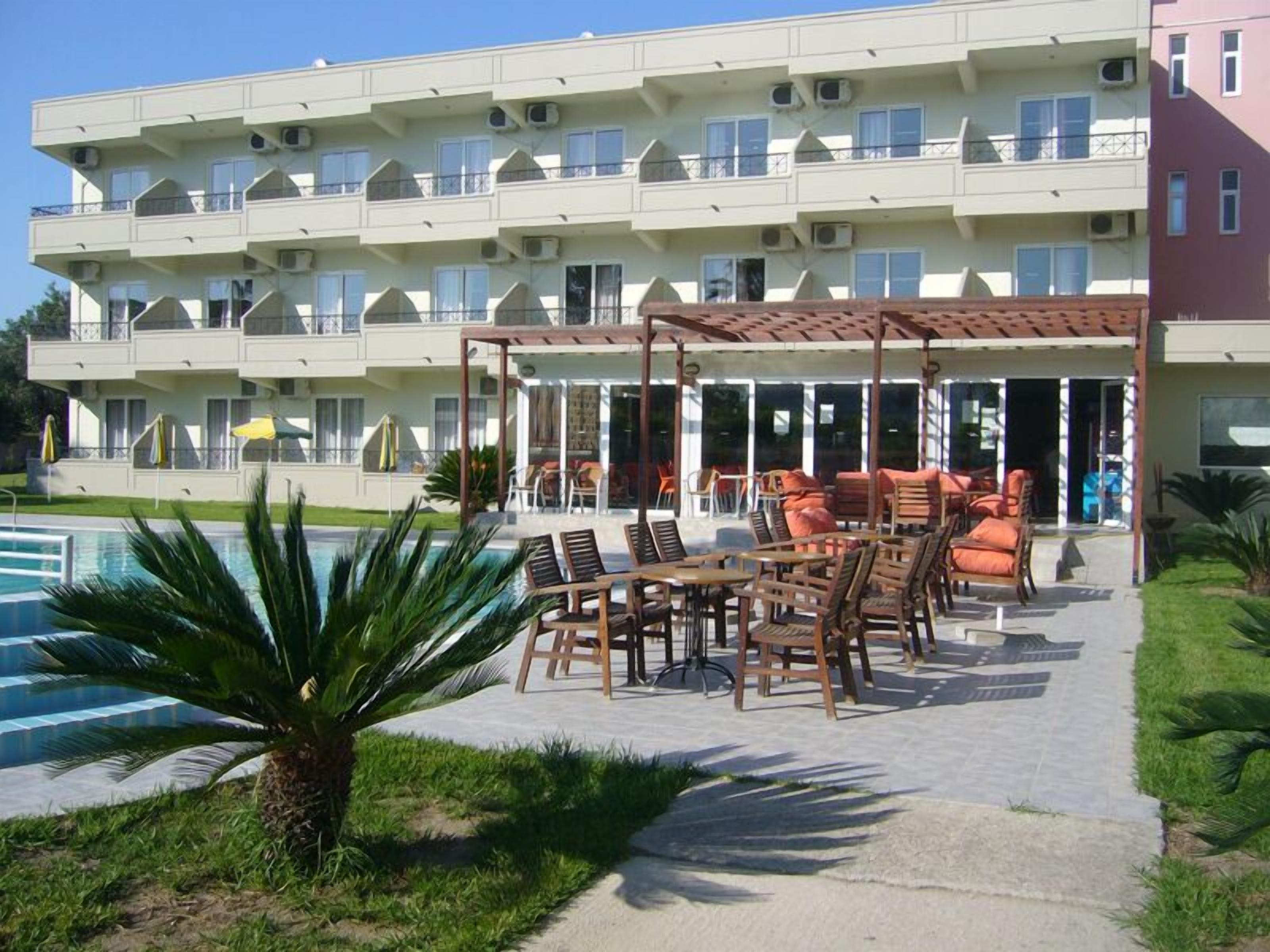 A multi-story hotel with outdoor seating and a pool.