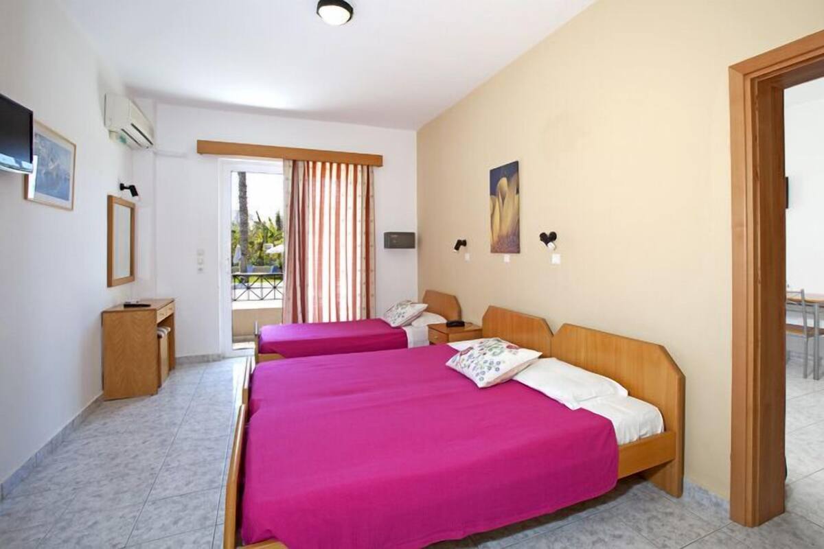 Habitación de hotel con dos camas, un escritorio, una silla y vistas al exterior.