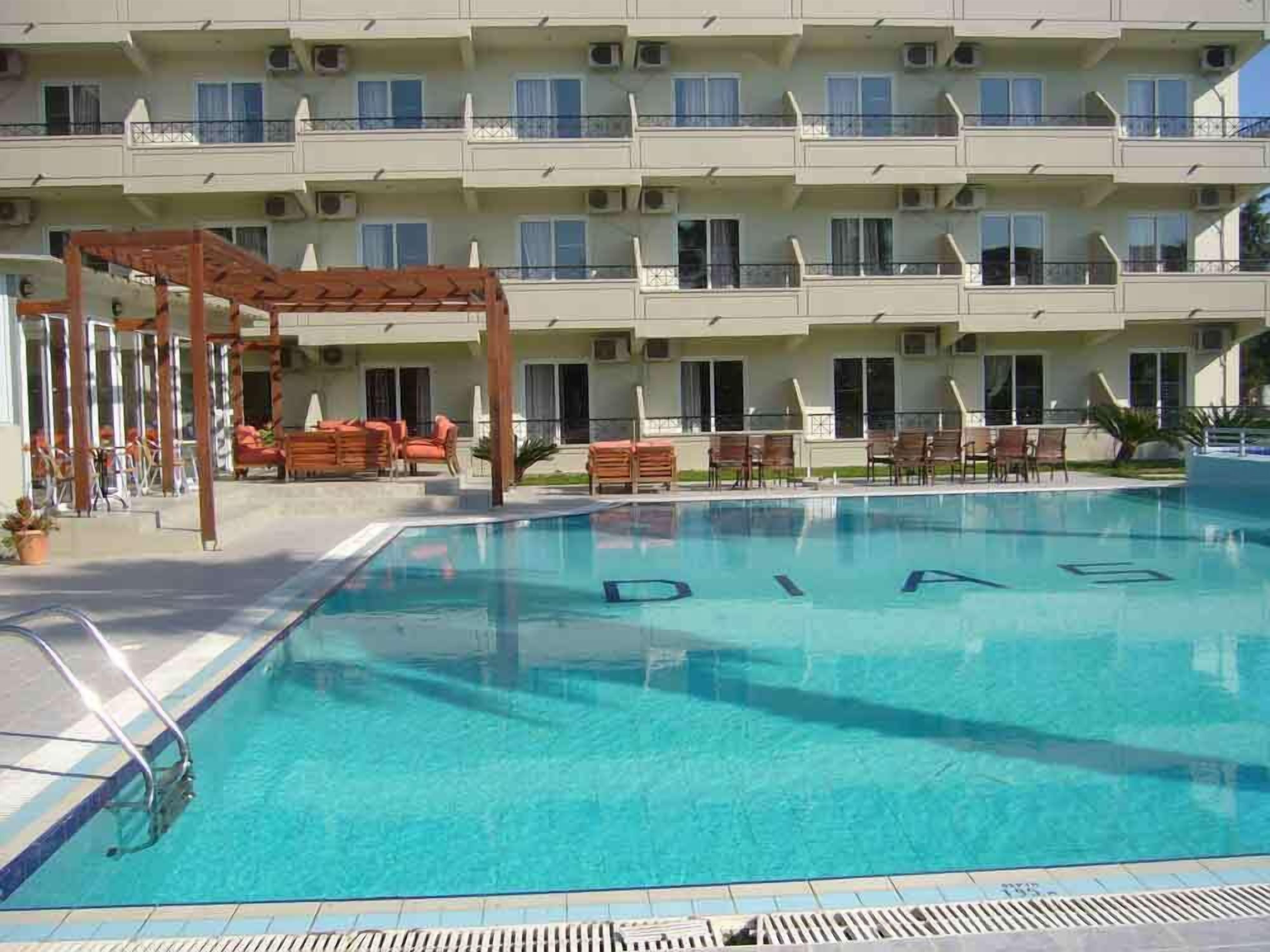 Une piscine avec une pergola et des chaises longues devant.