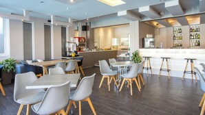A modern restaurant with a bar area, seating arrangements, and a kitchen in the background. - Dias Studios (Rhodes)
