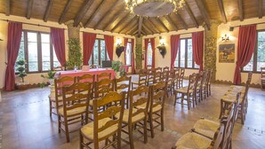 A spacious hall with wooden chairs and tables, a chandelier, and windows with red curtains. - Las Mayoralas (Periana)