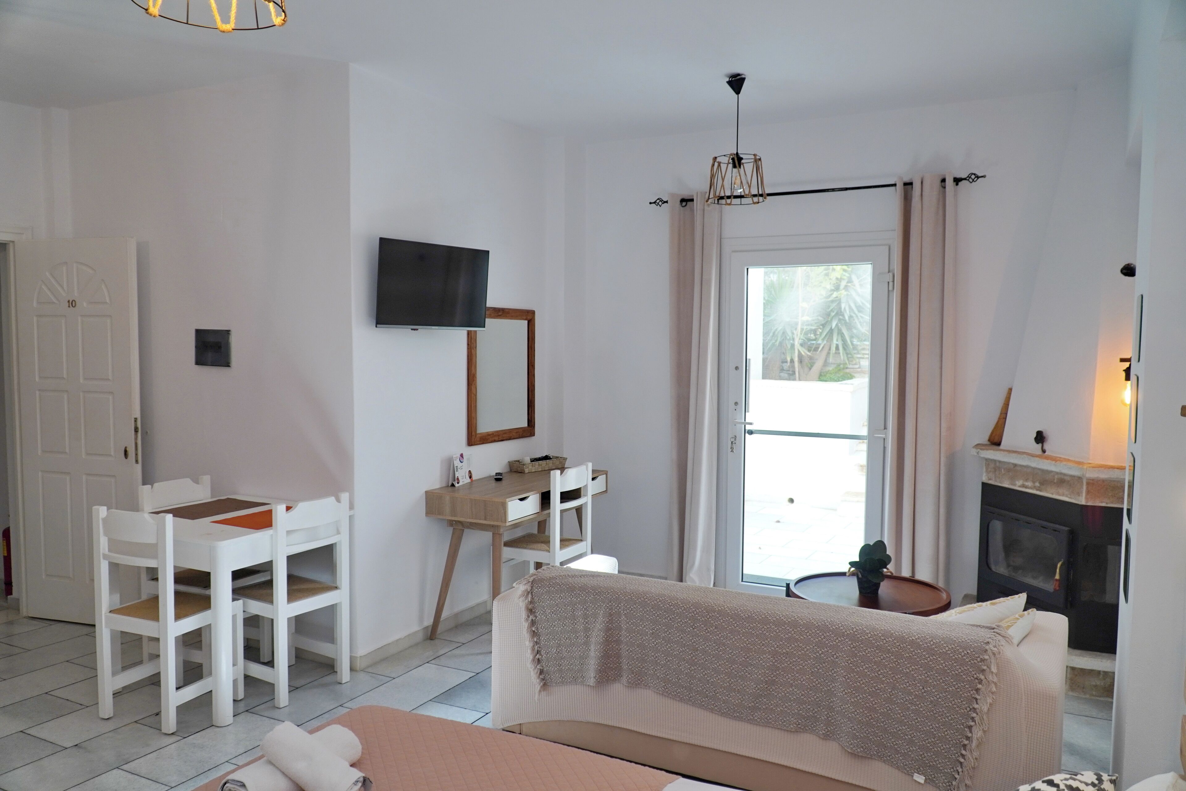A room with a bed, a desk, a chair, a television, and a fireplace.