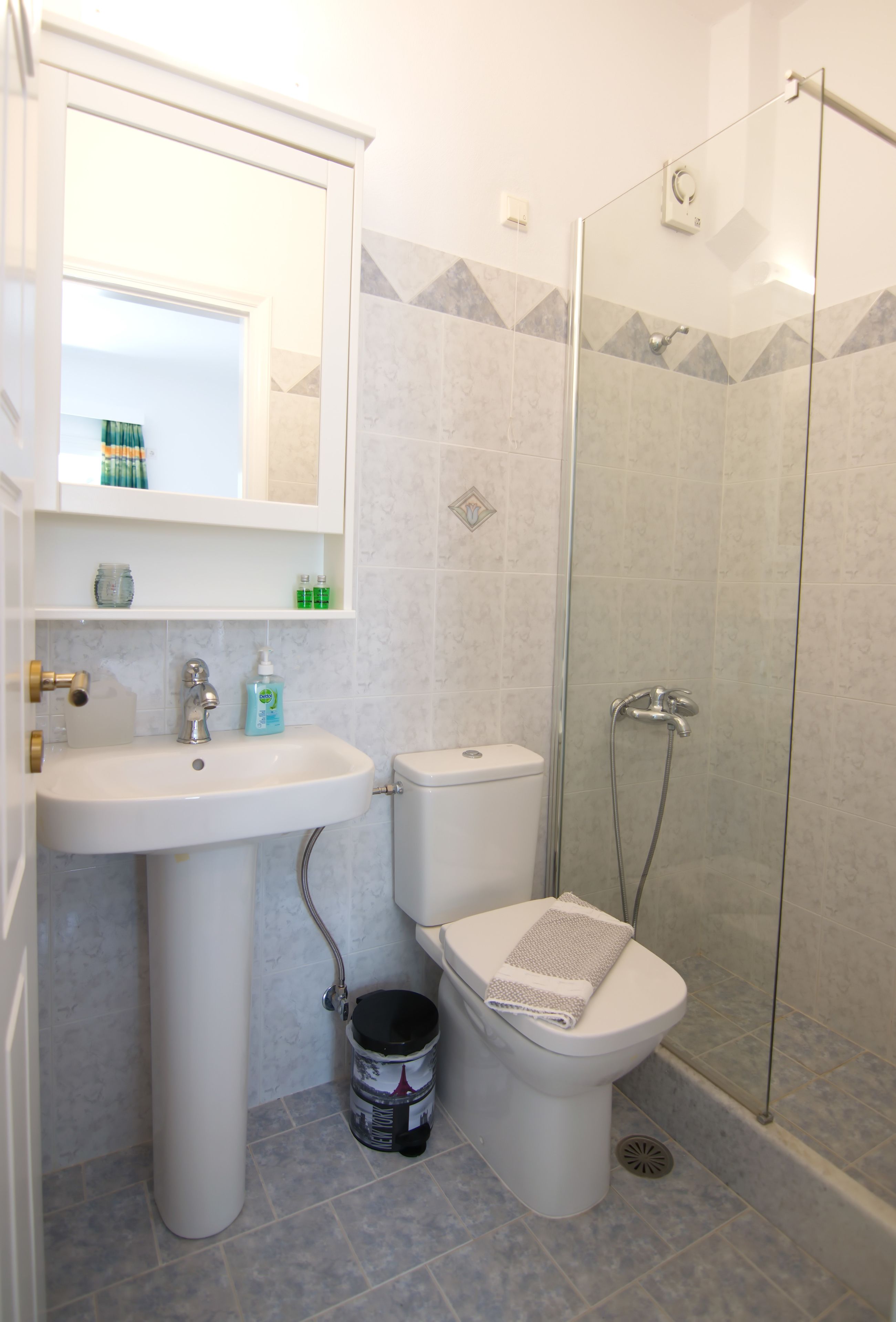 Un baño con lavabo, inodoro y cabina de ducha con mampara de vidrio.