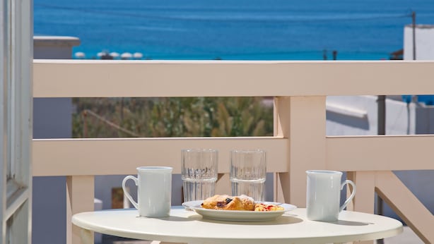 A balcony with a table set for two, overlooking a coastal view. - Camara Hotel (Naxos)