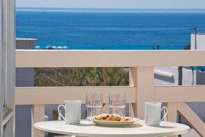 Un balcon avec une table dressée pour deux personnes, offrant une vue sur la côte.