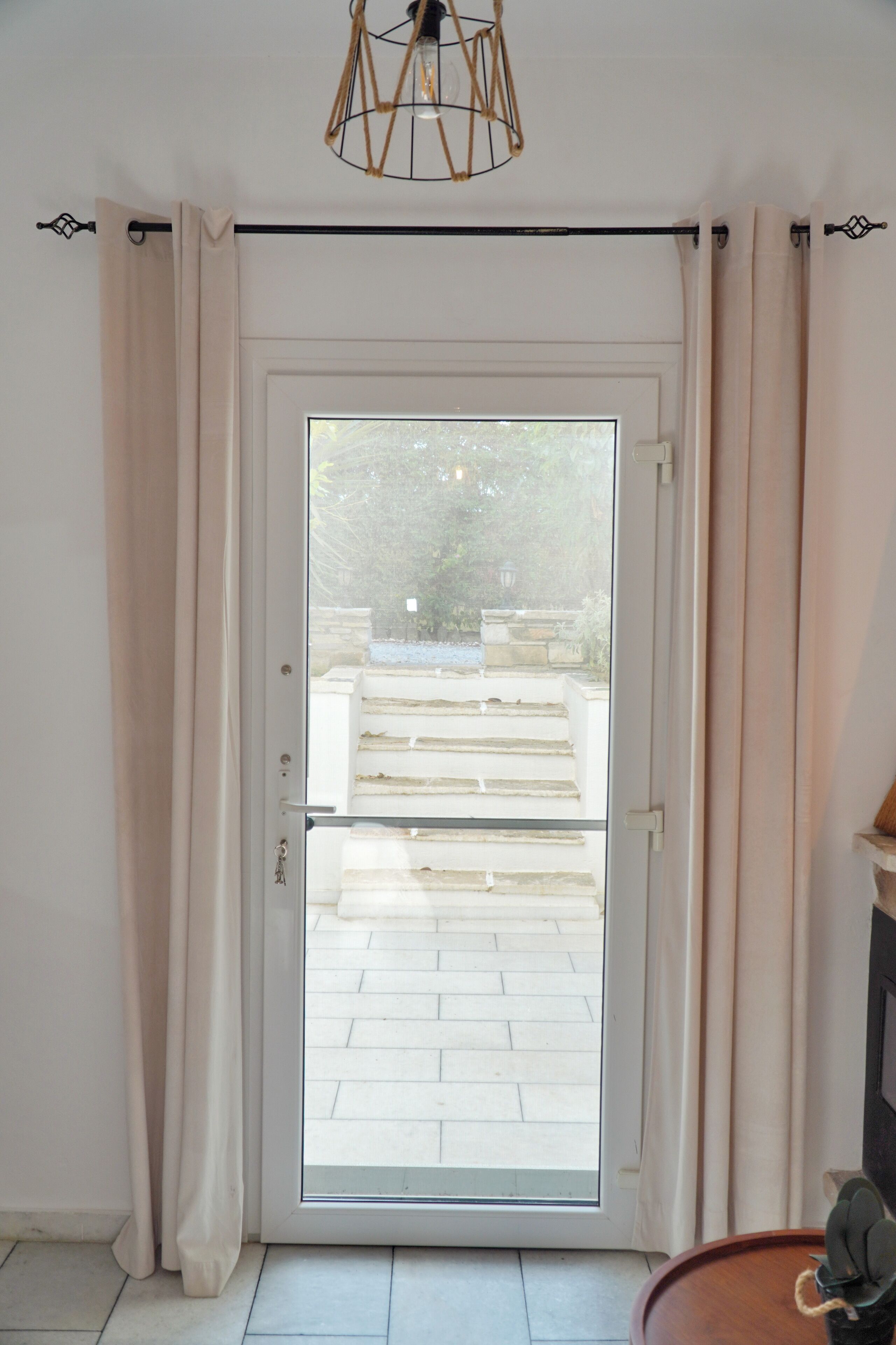 A room with a sliding glass door leading to an outdoor area with stone steps and a garden.
