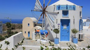 A building with a windmill, a blue door, and a sign that reads "Maria's Place". - Maria's Place - Adults Only (Oia)