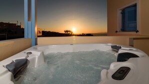 A hot tub with a sunset view, a window with blue shutters, and a control panel. - Maria's Place - Adults Only (Oia)