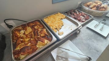 A buffet with various food items including baked goods and macaroni and cheese.