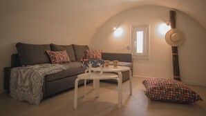A cozy living room with a sofa, a small white table, and a patterned cushion. - Maria's Place - Adults Only (Oia)