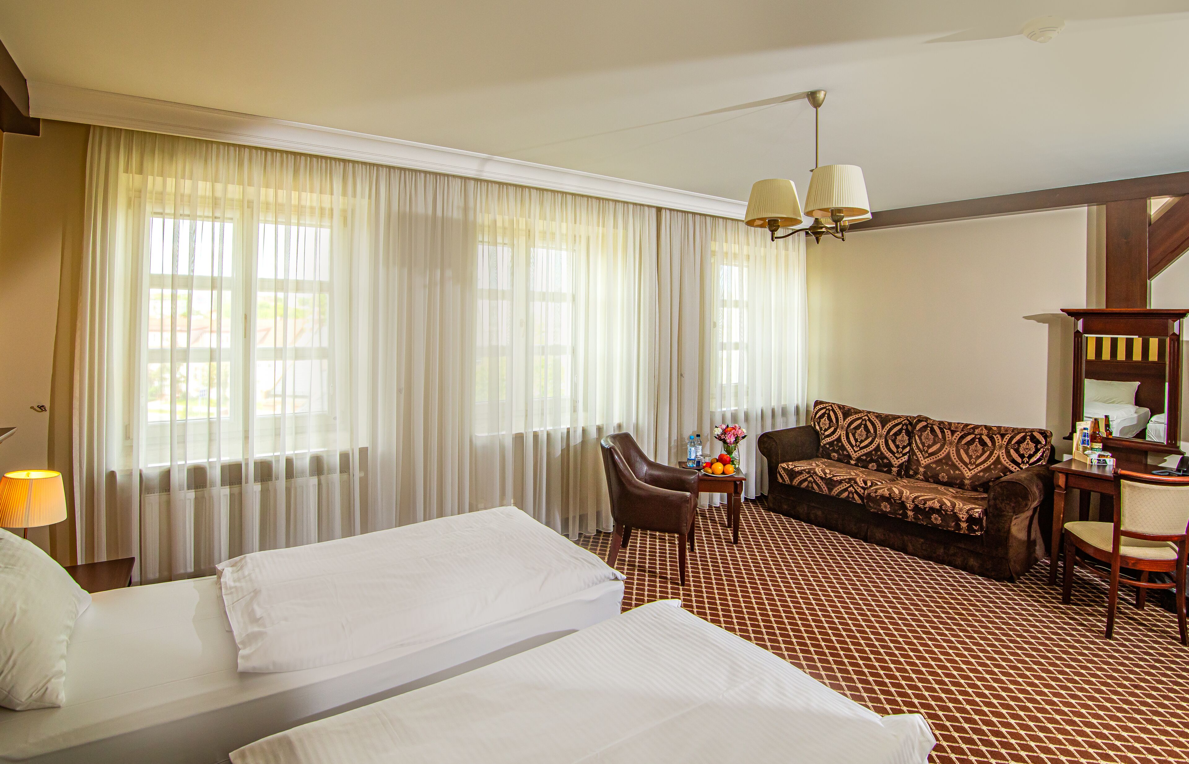 Ein Hotelzimmer mit zwei Betten, einem Sofa, einem Schreibtisch und einem Stuhl.